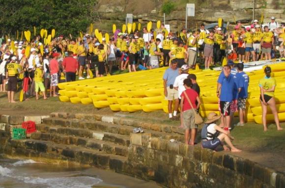 Team kayaks stacked on shore ready to start