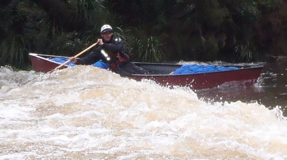Travis paddling onto the standing wave at the weir